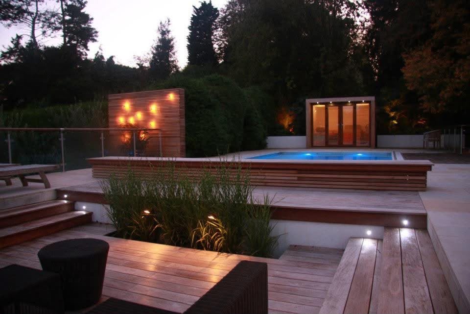 Completed pool garden at night, with lit renovated pool, hardwood decking, sandstone paving, wide lit steps and a slatted timber screen